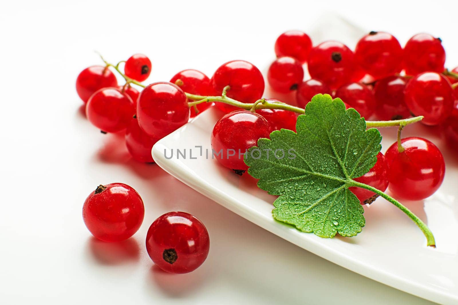 Fresh red currant berries with leaf on wooden background close up