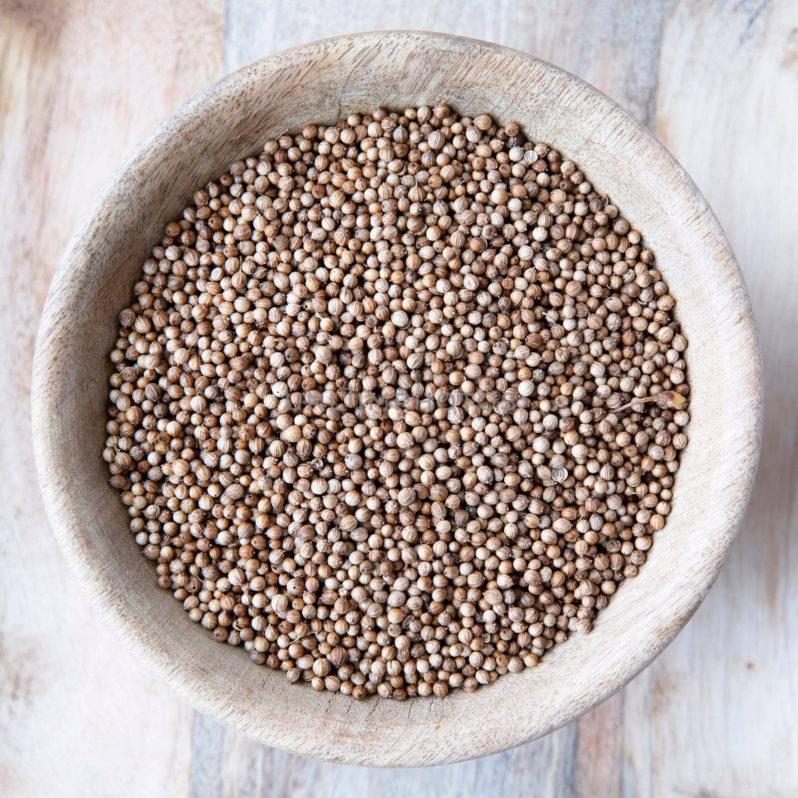 Flat lay wooden bowl of whole coriander seeds
