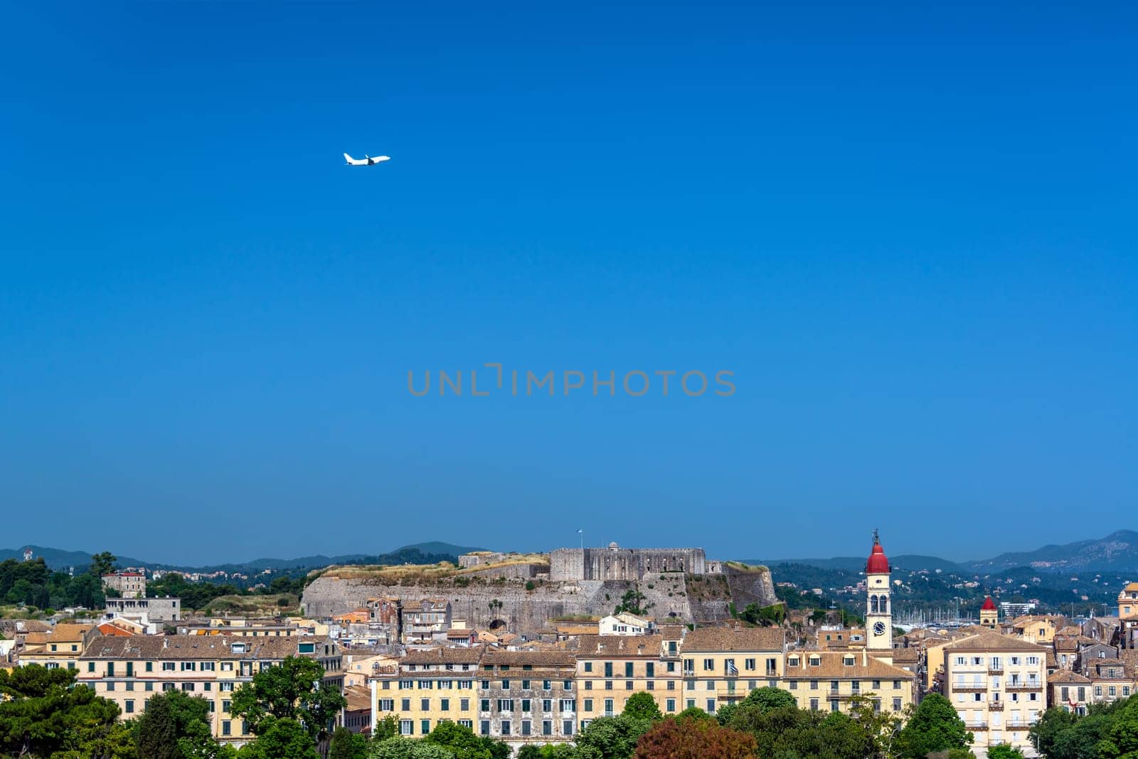 Airplane flying over the old town of Corfu, Greece with the New Fortress in the background