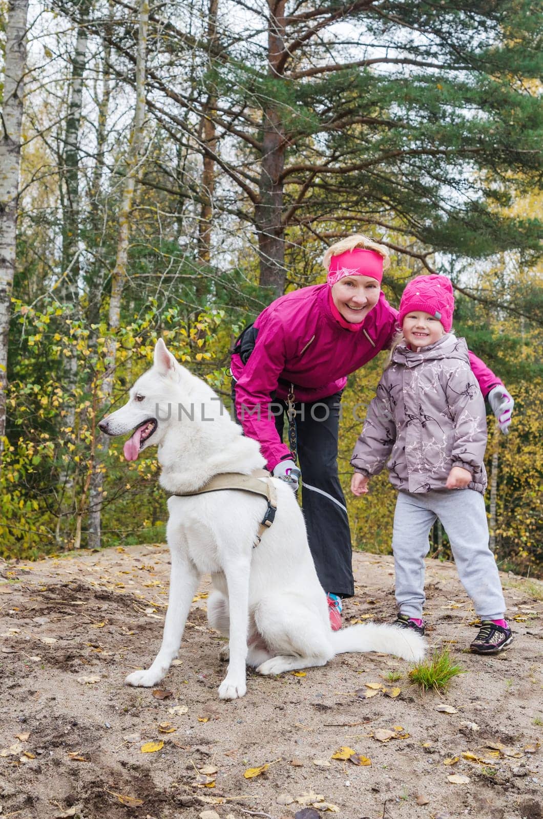 Granny with her granddaughter and a dog walk in autumn Park