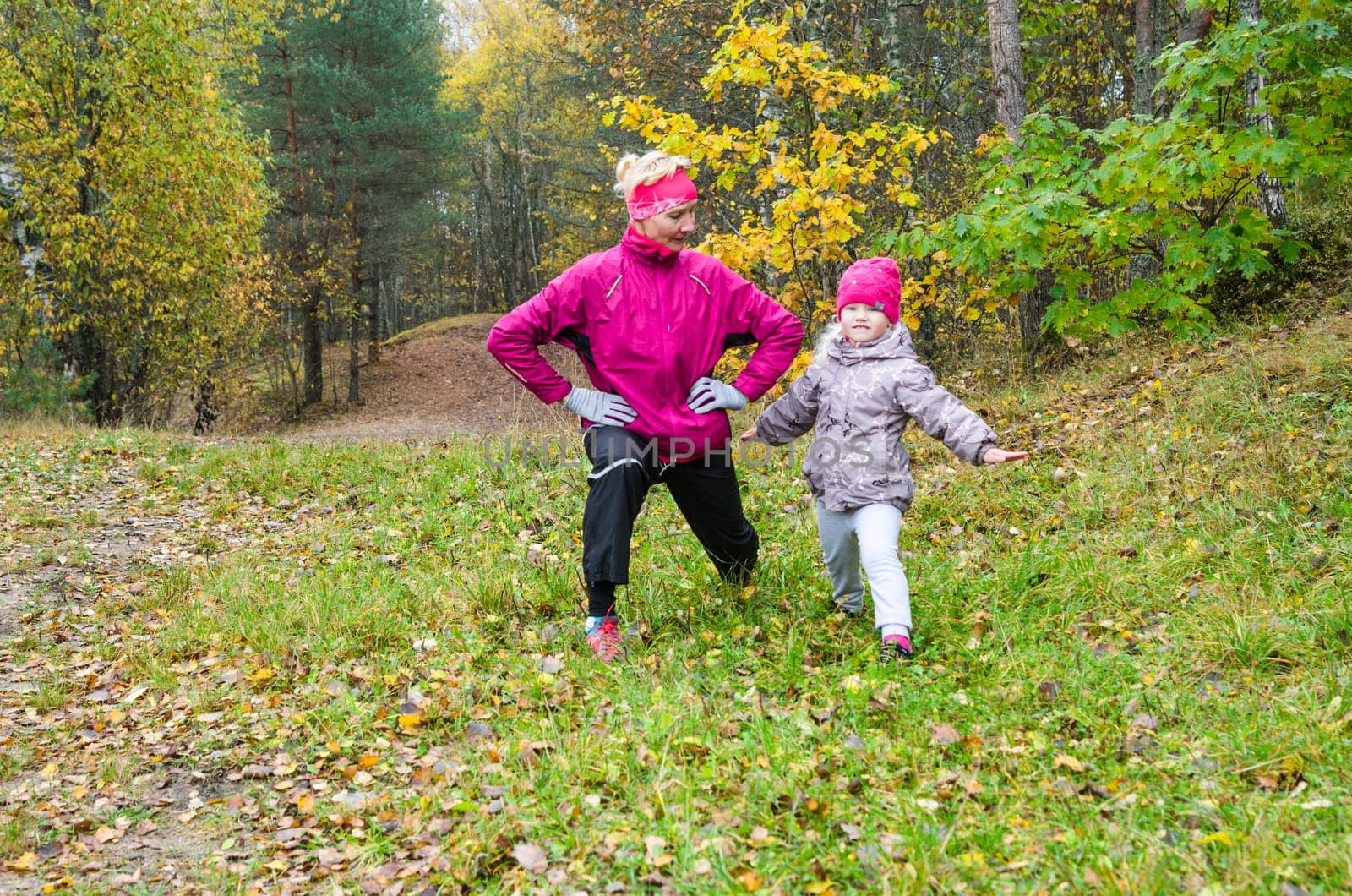 Woman with girl doing aerobics in the autumn park