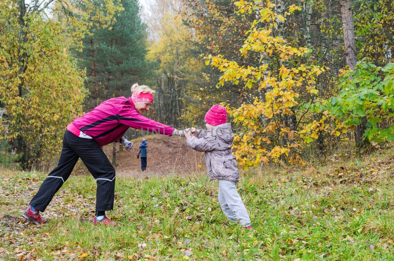 Woman with girl doing aerobics in the autumn park