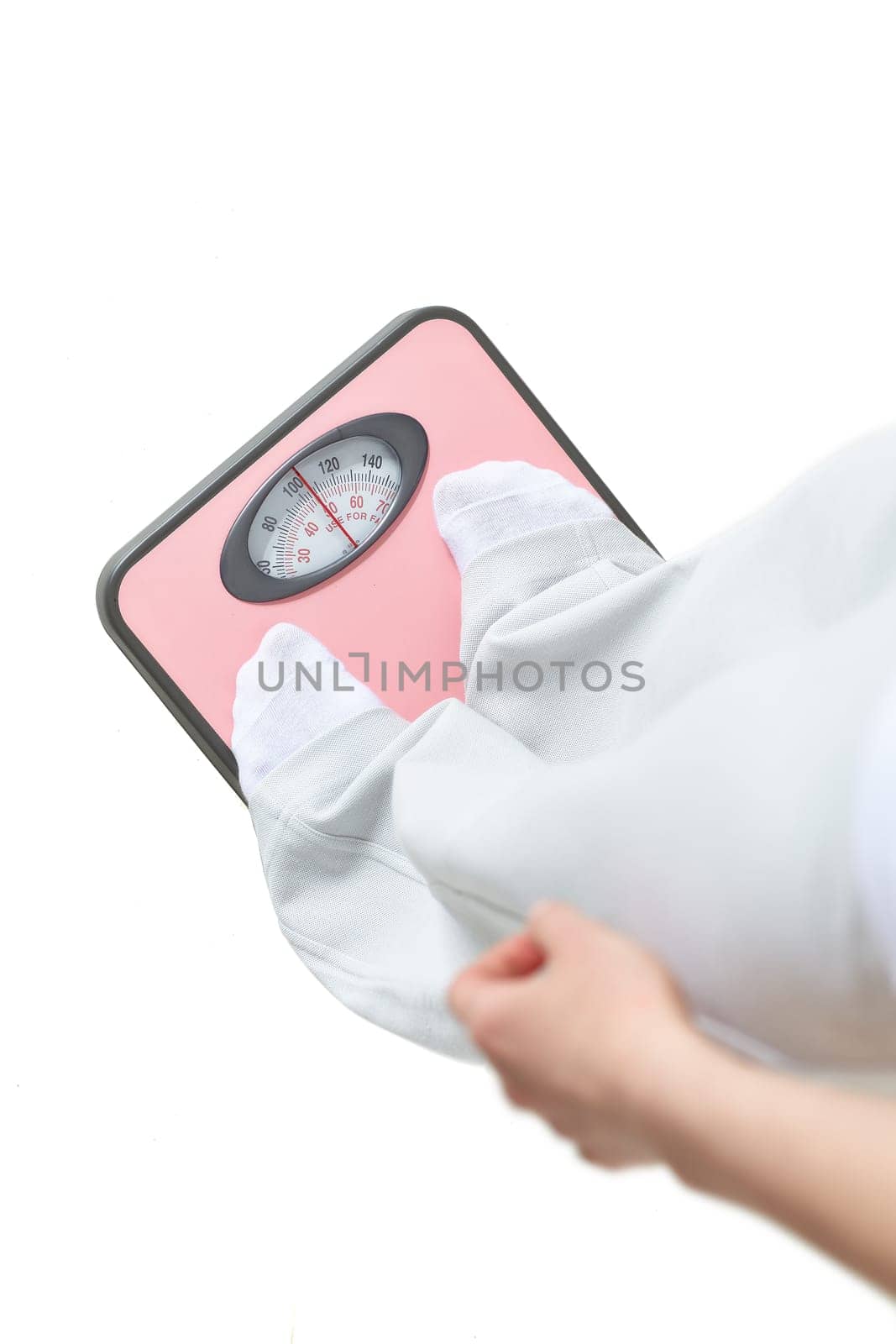 Young woman stands on scales and measures weight on a white background. Concept of healthy lifestyle.