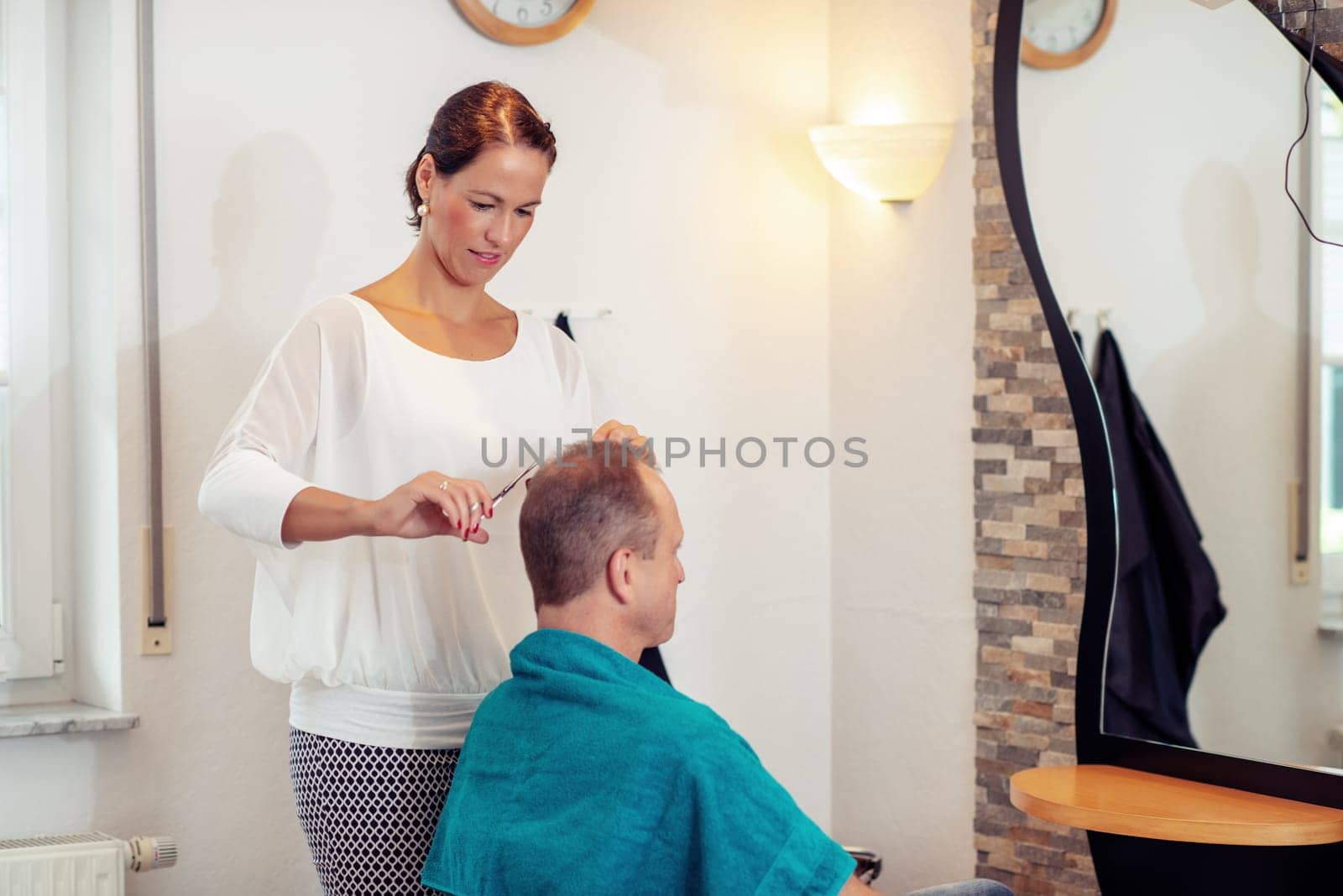female hairdresser cutting hair of man in her shop