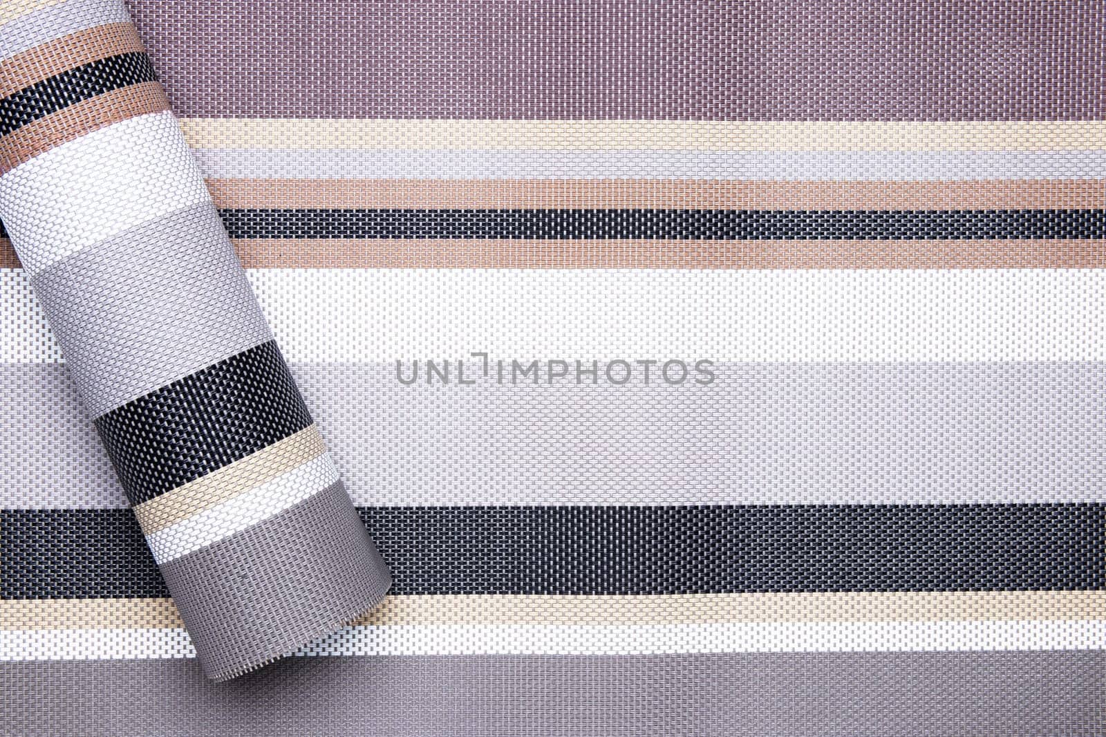 Striped background. Top view of details of colorful horizontal striped and a role of same pattern on left background texture with seamless pattern on plastic tissue. Macro.