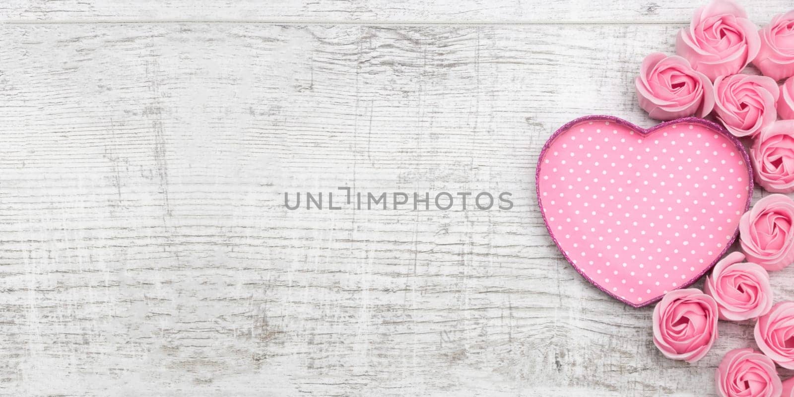 Pink roses and note paper on the wooden background