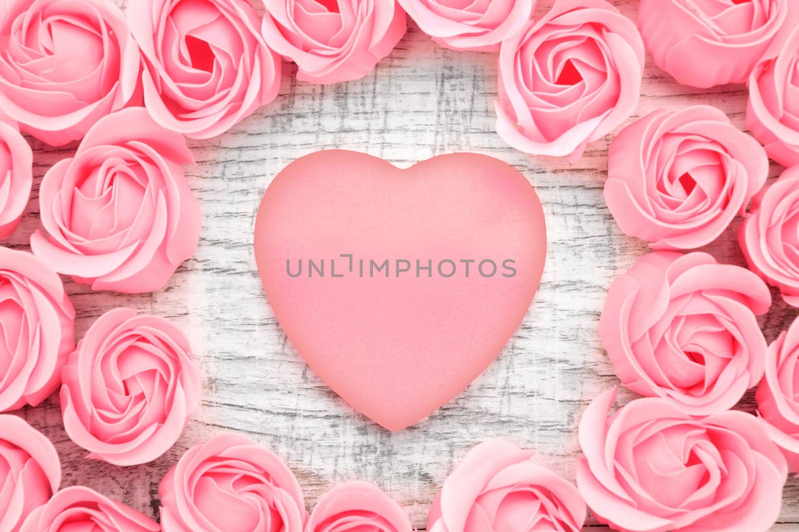 Pink roses and note paper on the wooden background