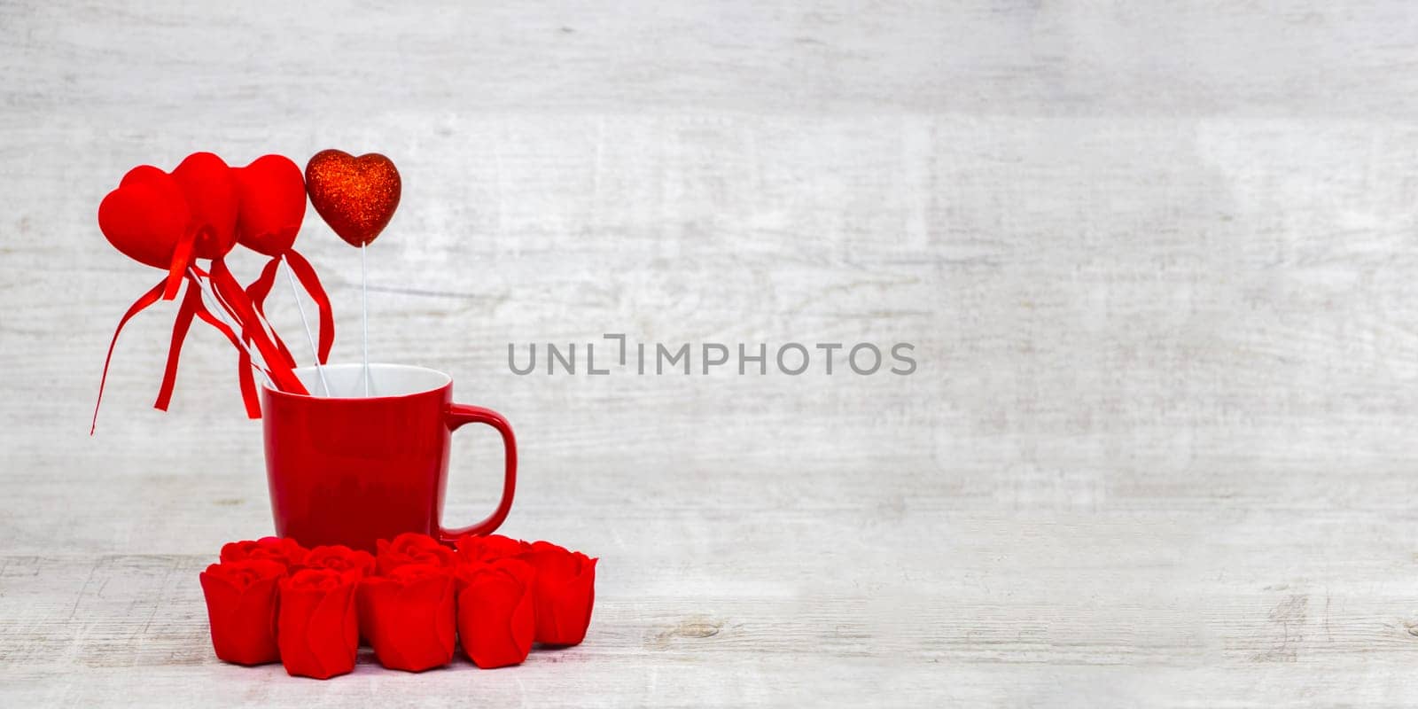 Shiny red coffee cup and red roses on wooden background