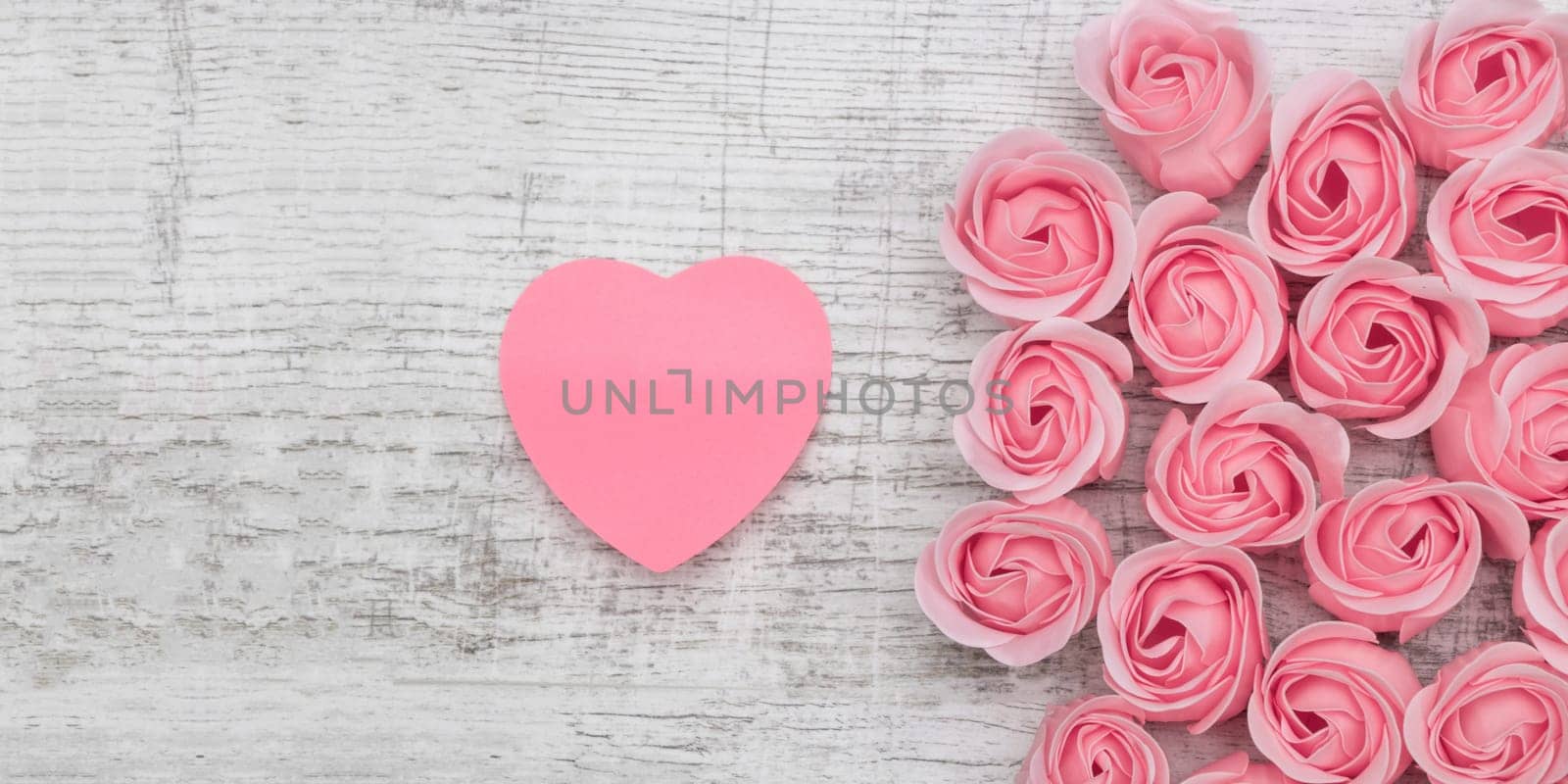 Pink roses and note paper on the wooden background
