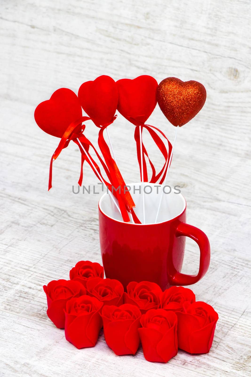 Shiny red coffee cup and red roses on wooden background