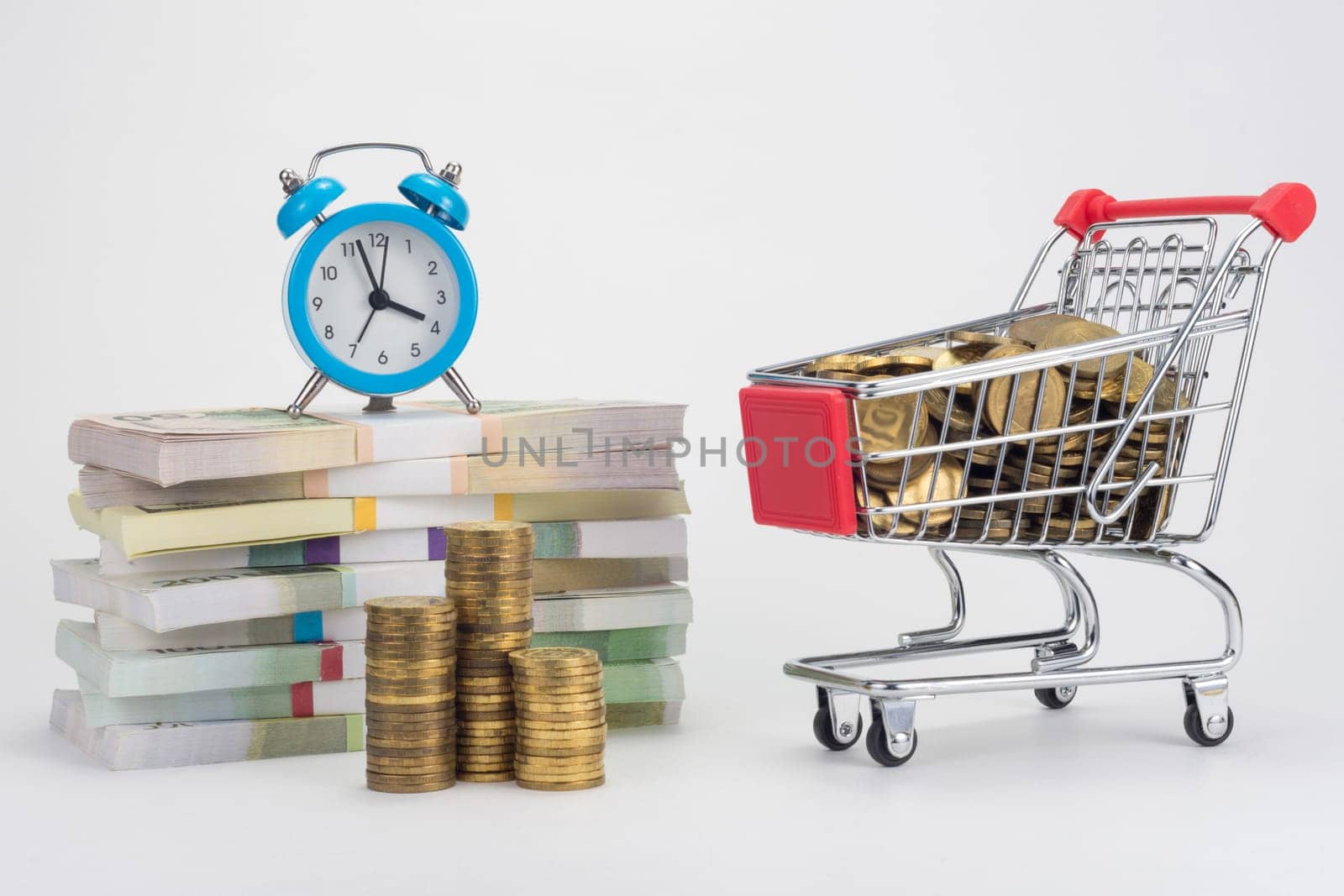 Piles of money, an alarm clock is on them, a trolley with coins