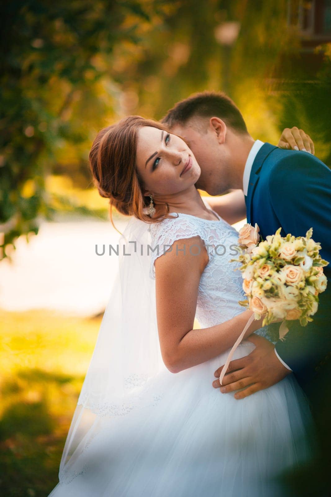 couple groom and bride hugging and kissing on nature park background.
