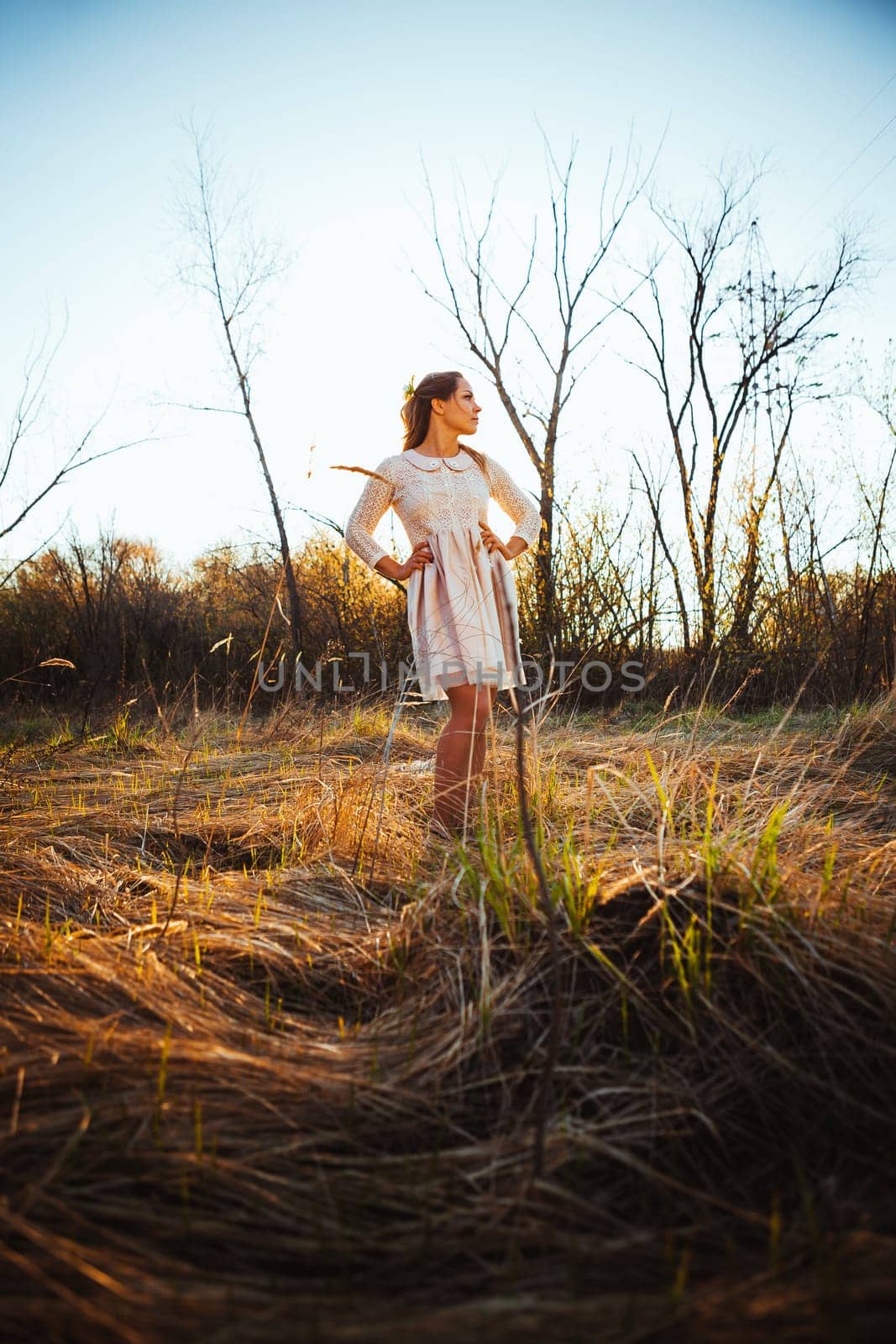 Beautiful girl standing in a field on a sunset background.