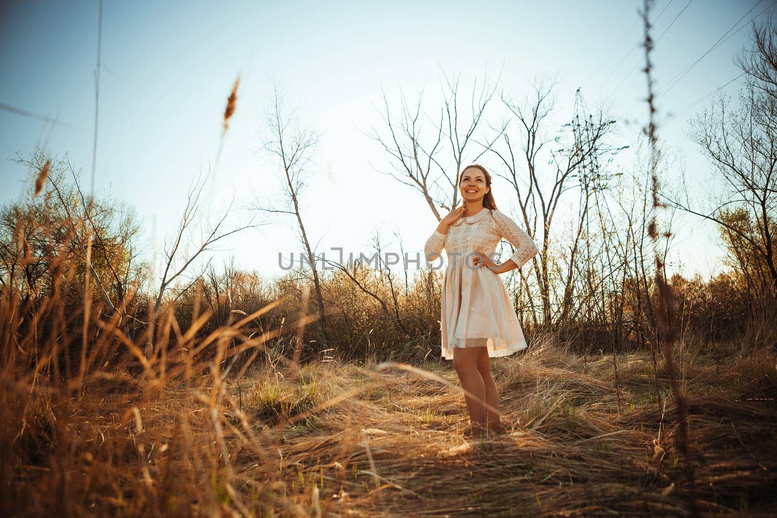 Beautiful girl standing in a field on a sunset background.