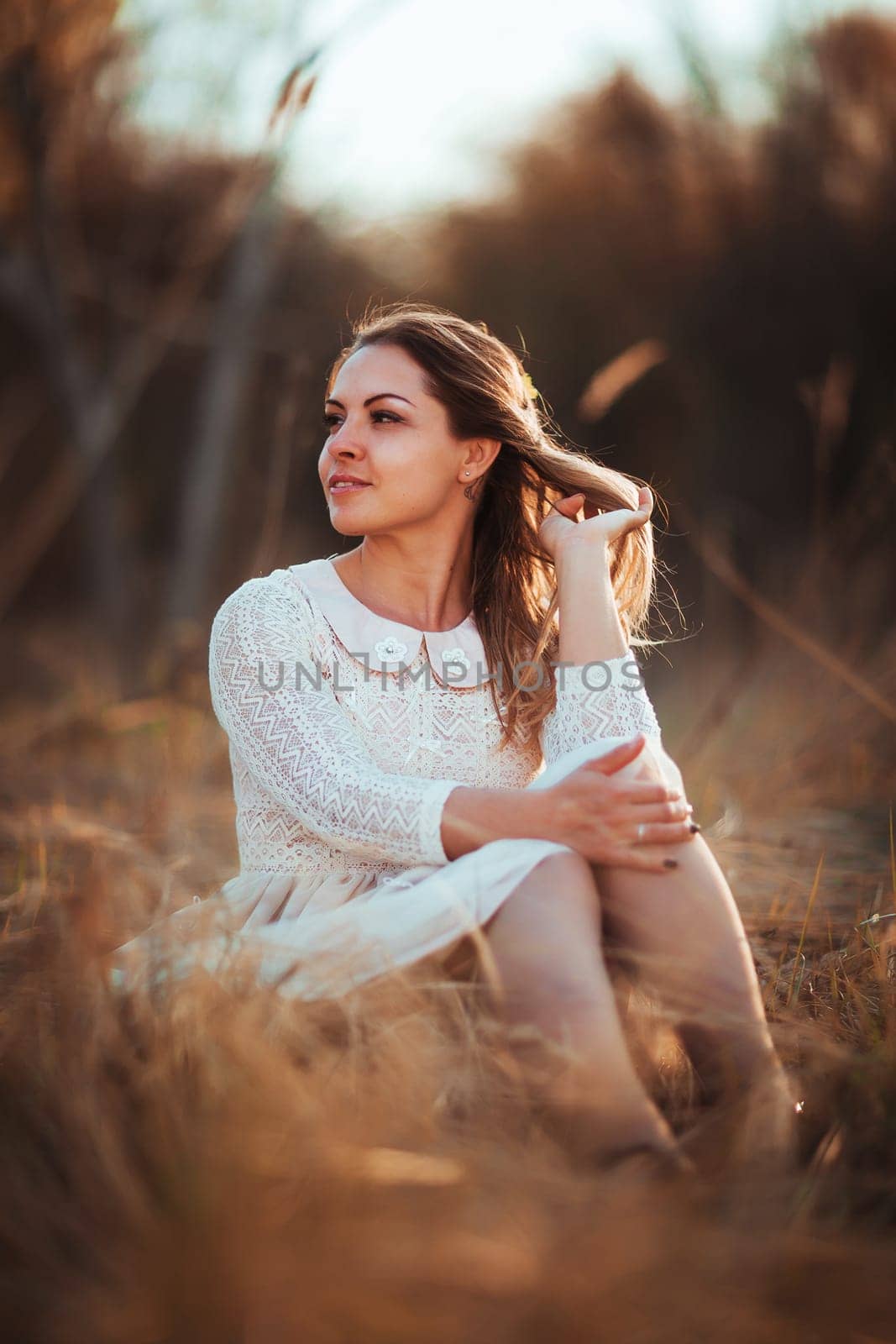 girl is sitting in the field on the sunset background.