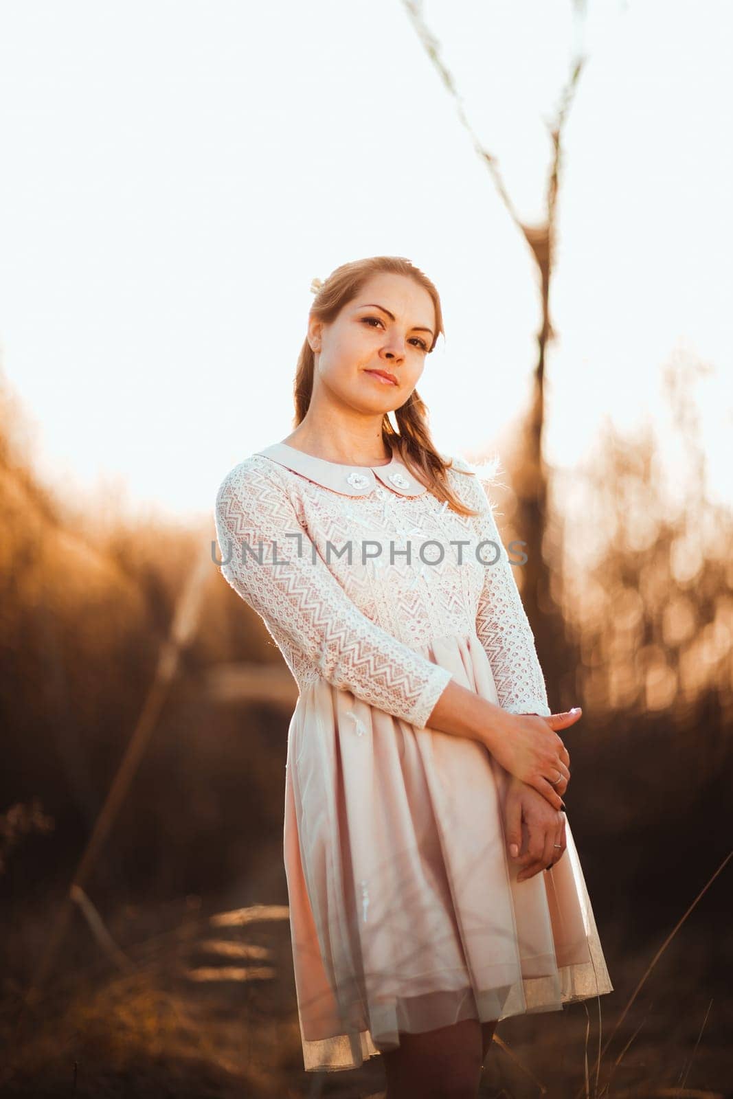 Beautiful girl standing in a field on a sunset background.