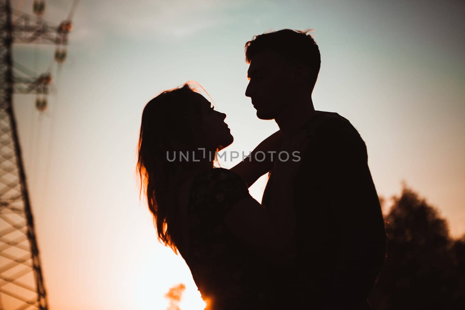 Silhouettes of a guy and girl in a field on a sunset background.