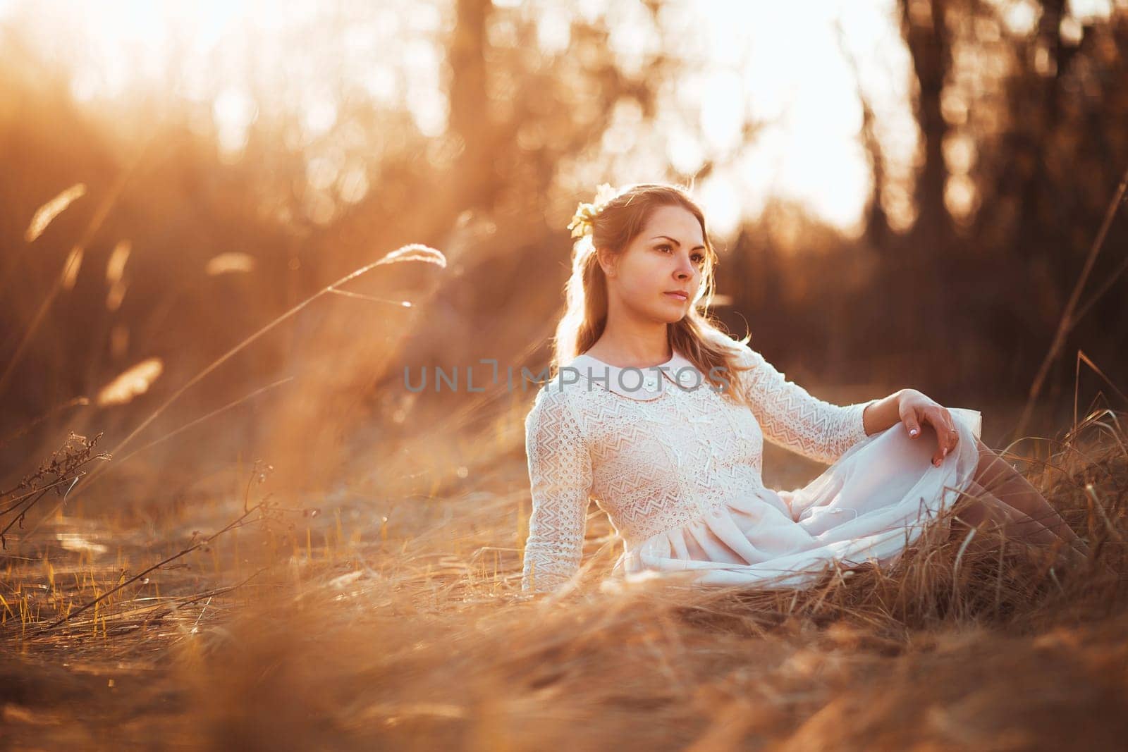 girl is sitting in the field on the sunset background.
