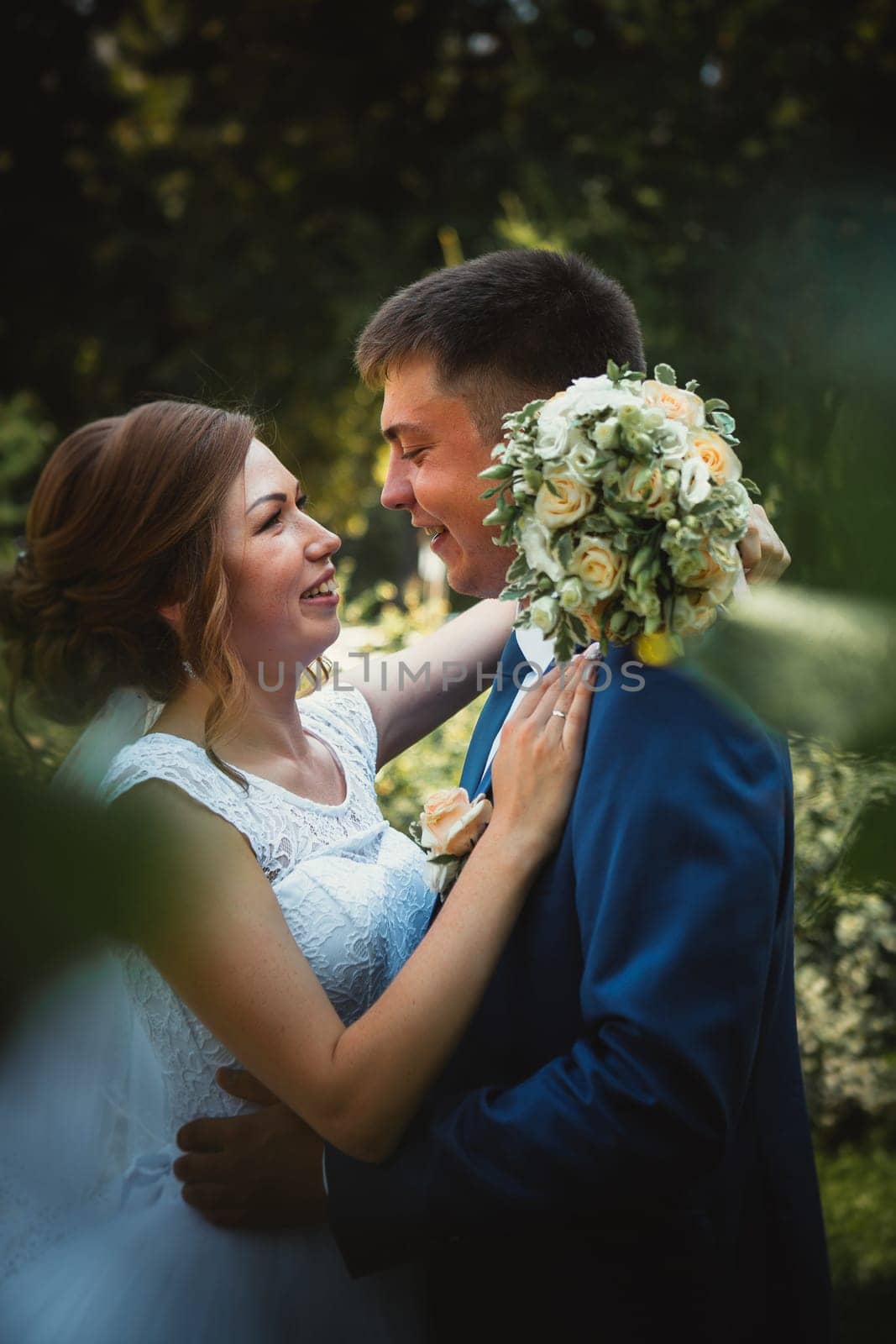 couple groom and bride hugging and kissing on nature park background.