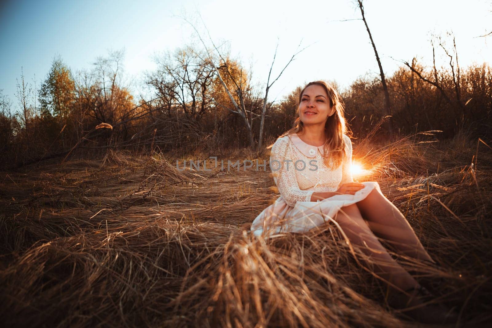 girl is sitting in the field on the sunset background.