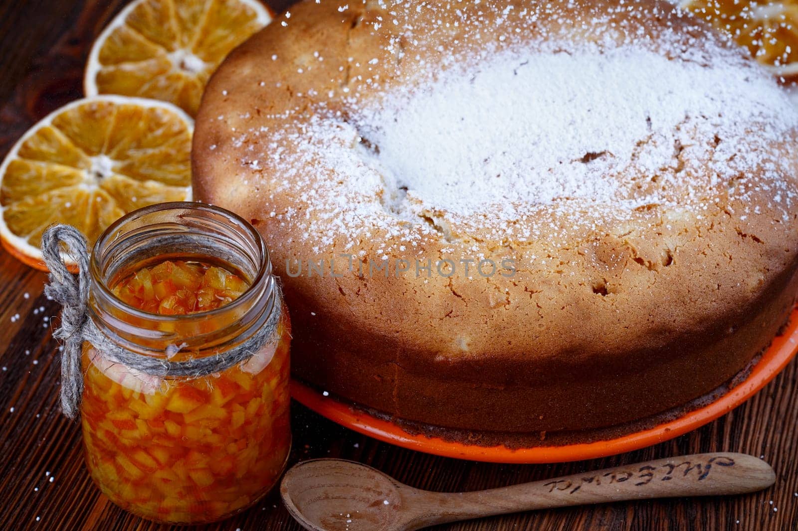 Muffin baked on a wooden table with a jar of candied orange
