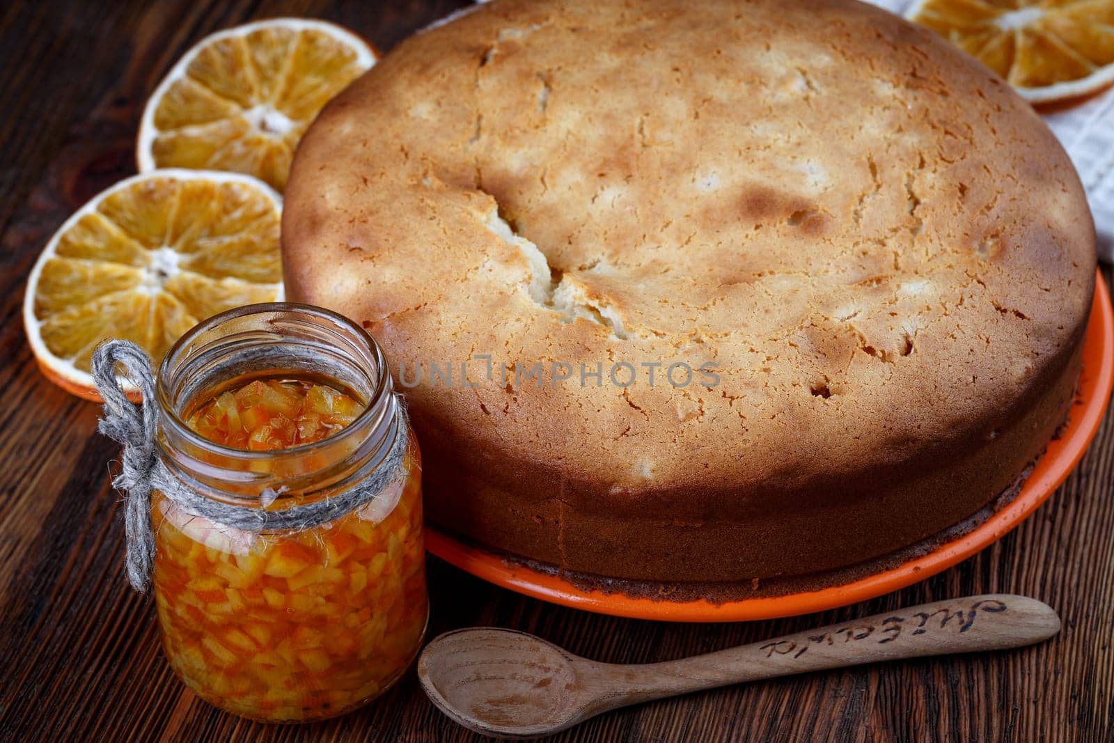 Muffin baked on a wooden table with a jar of candied orange