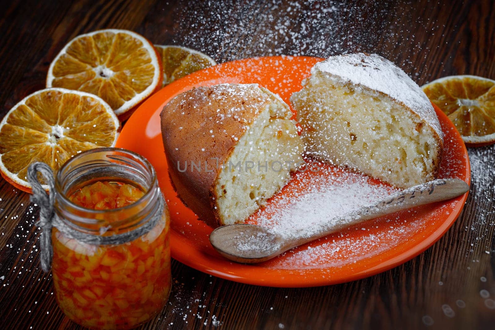 Slices of cake in a plate on a wooden table with a jar of candied orange
