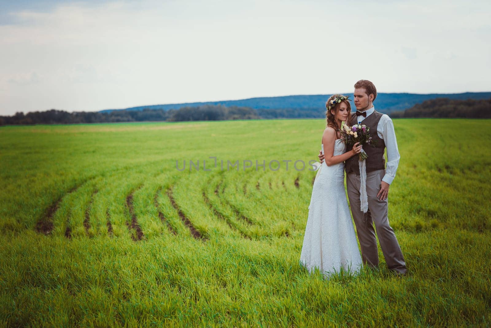 bride and groom stand on the background of the field.