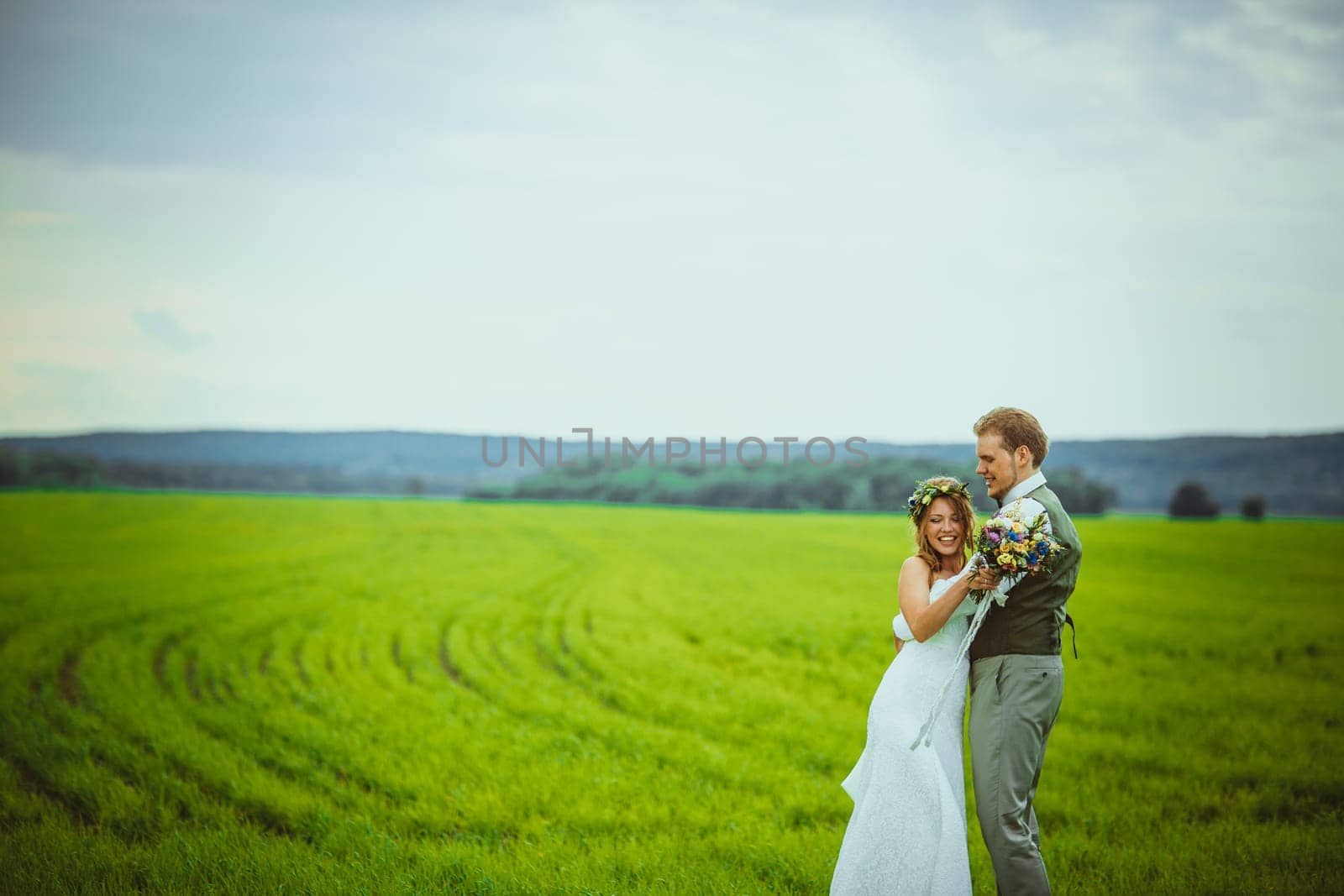 bride and groom stand on the background of the field.