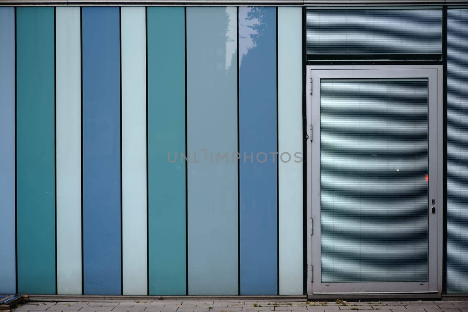 A modern house facade made of plastic panels with a door and metal blinds...