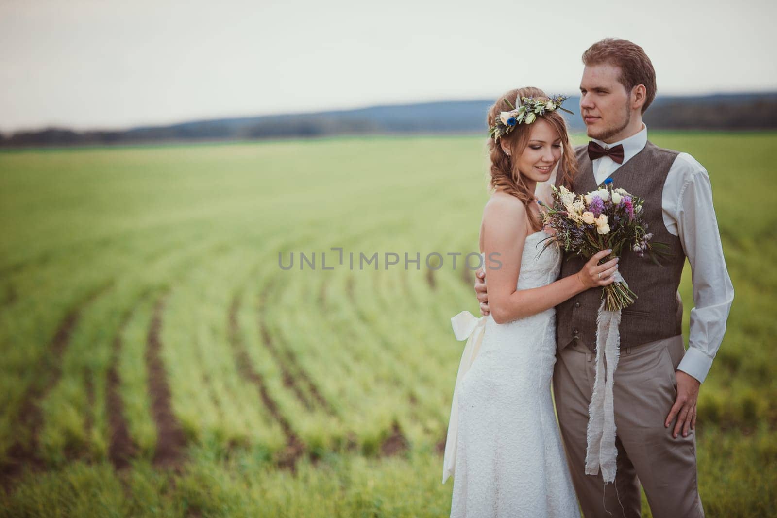 bride and groom stand on the background of the field.