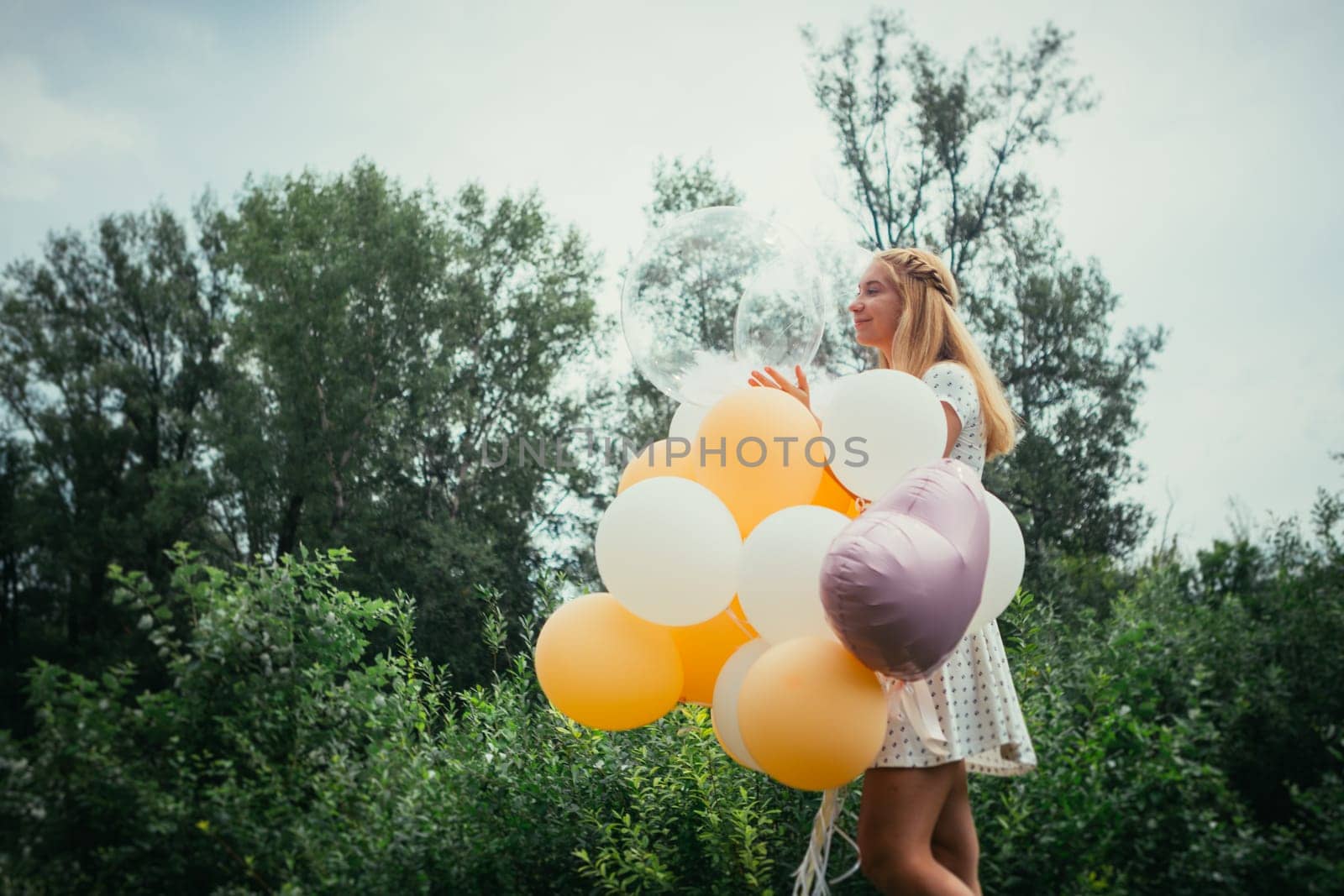 young girl with balloons on nature background.