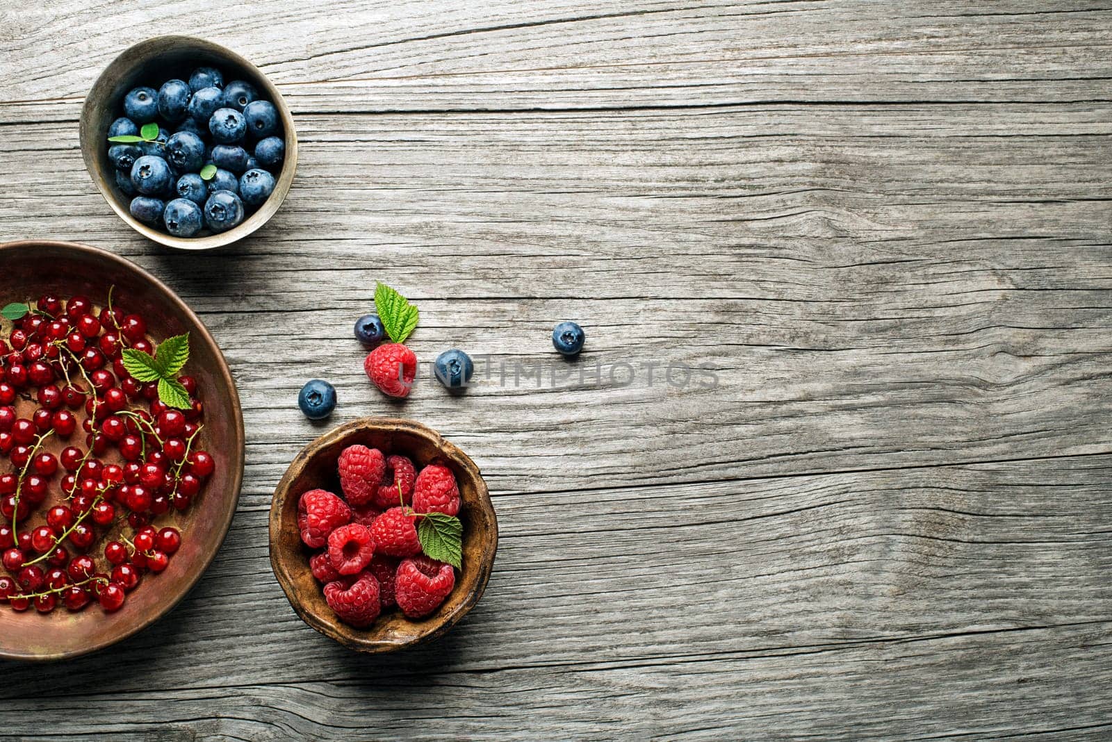 Mix of fresh berries in a bowl on wooden background