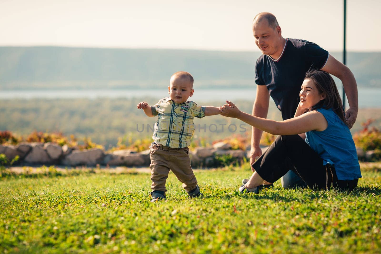 Happy family with baby on green grass.
