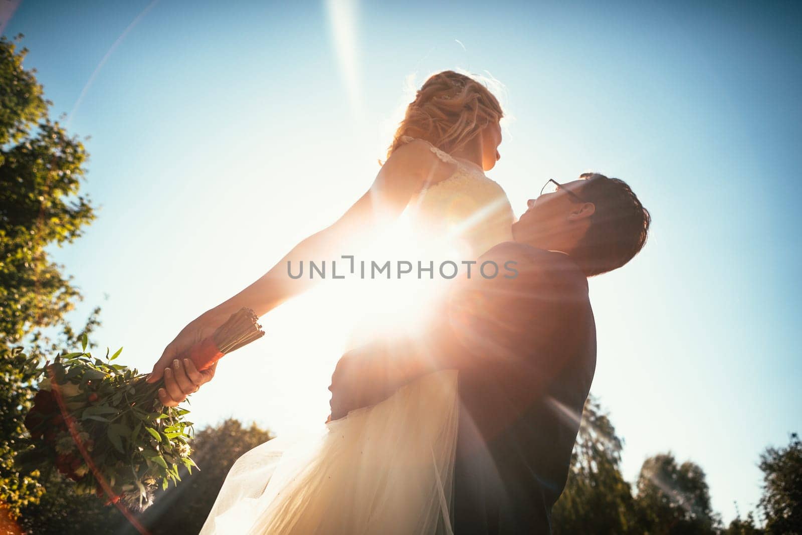 Dancing young bride and groom sunlight background.