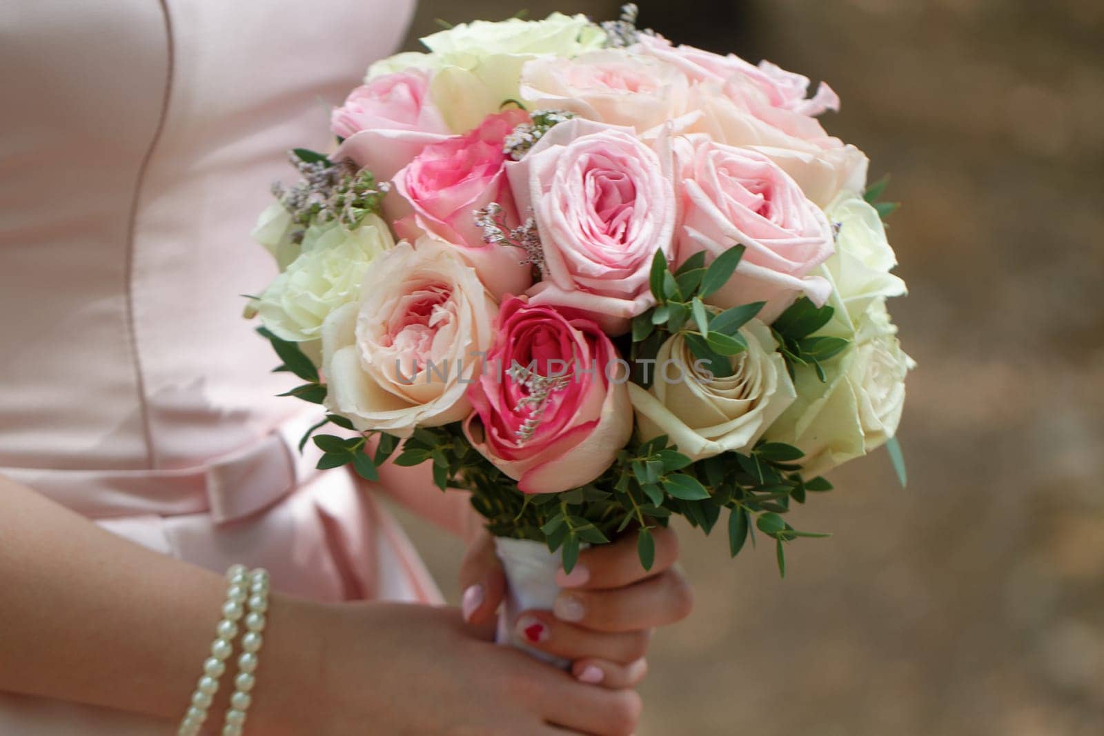 beautiful wedding bouquet of cream roses in hands of the bride.