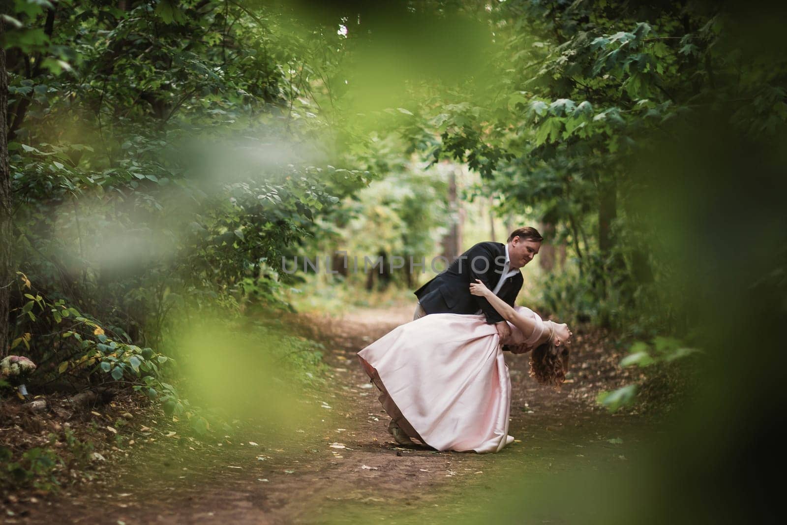 bride and groom dancing in the forest background and sunlight.