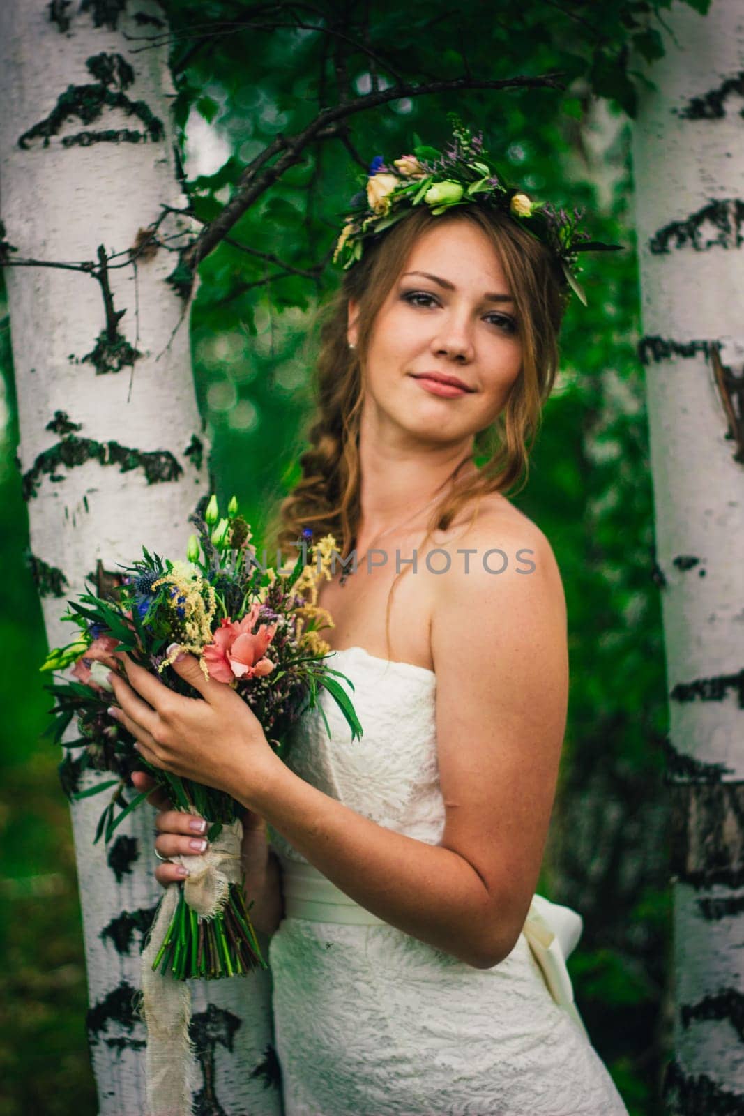 Young bride near birches in the forest.