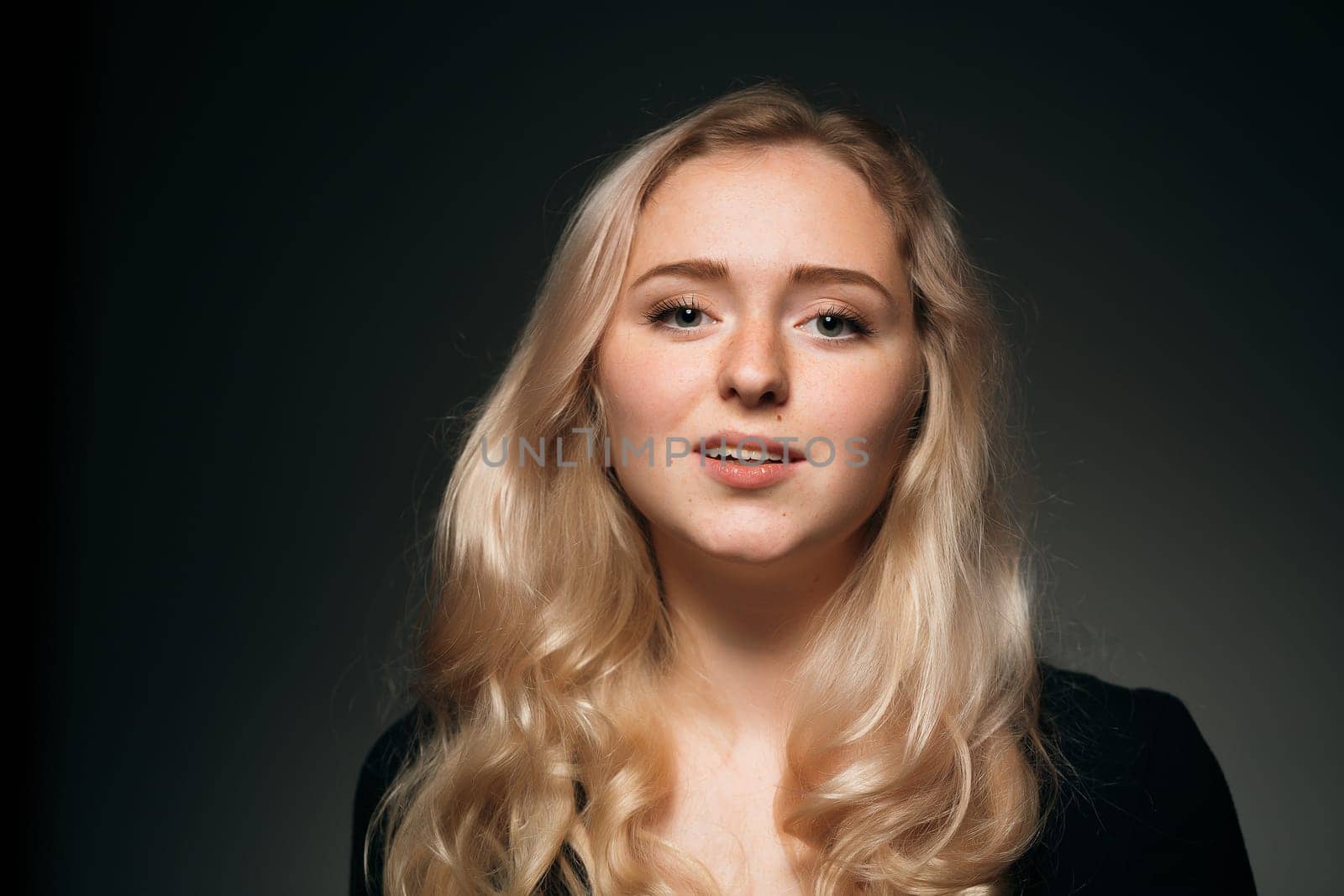 young girl blonde on a dark background.