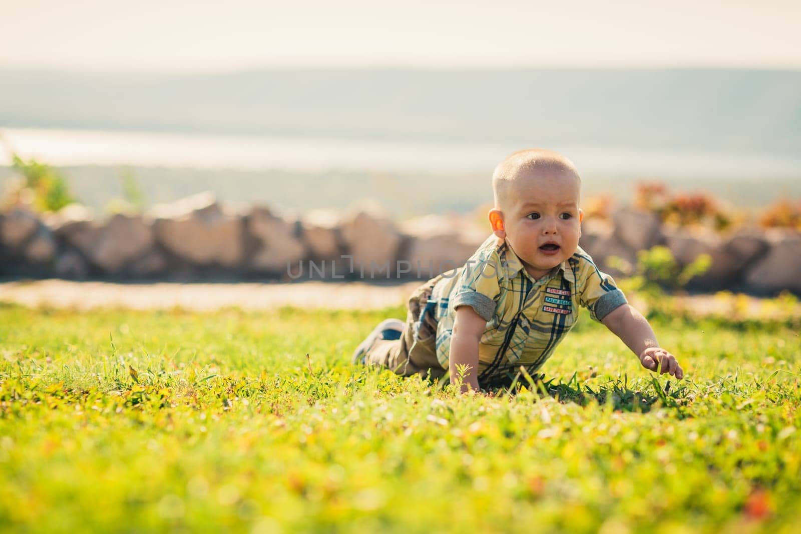 Baby boy on green grass nature background.