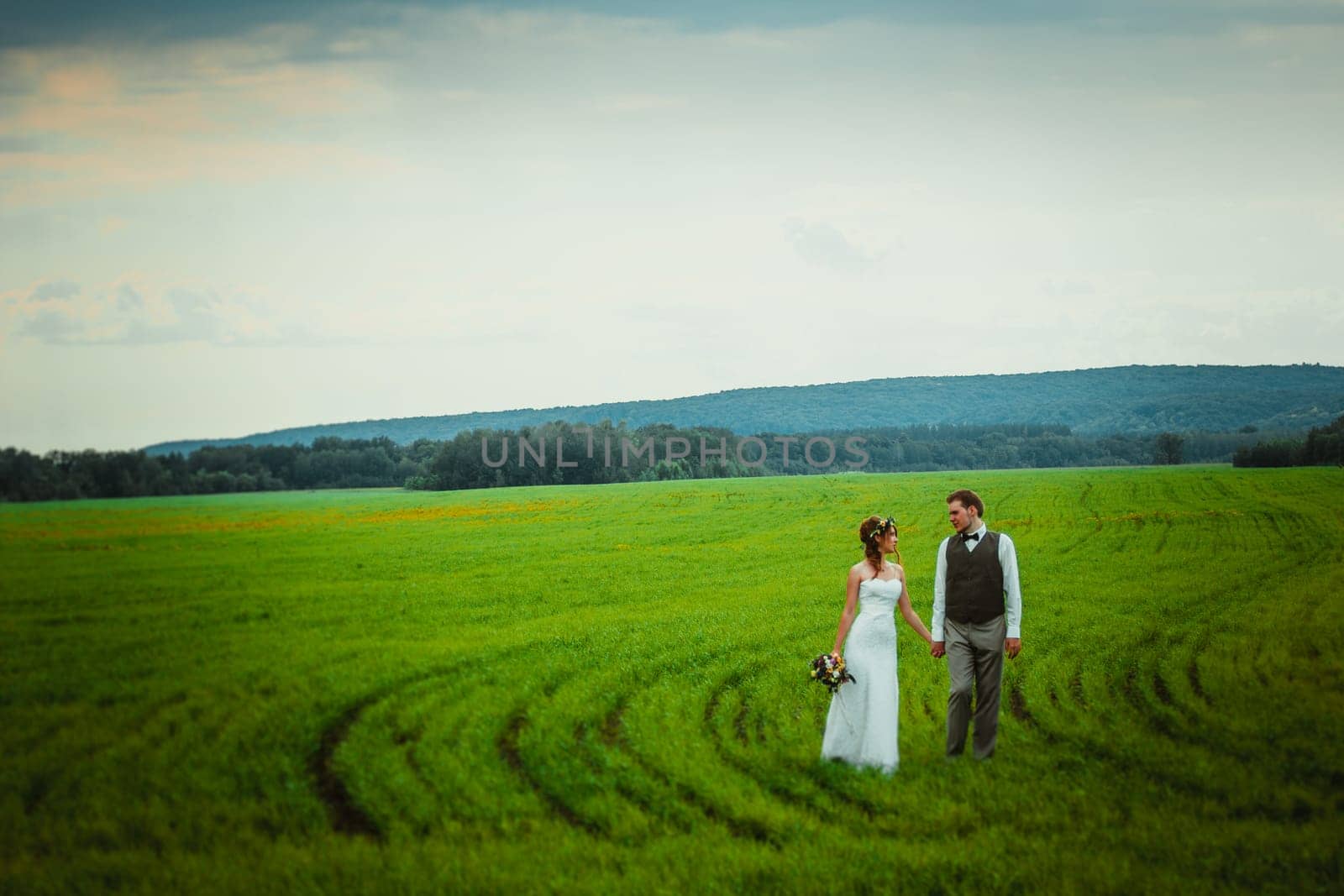 bride and groom stand on the background of the field.