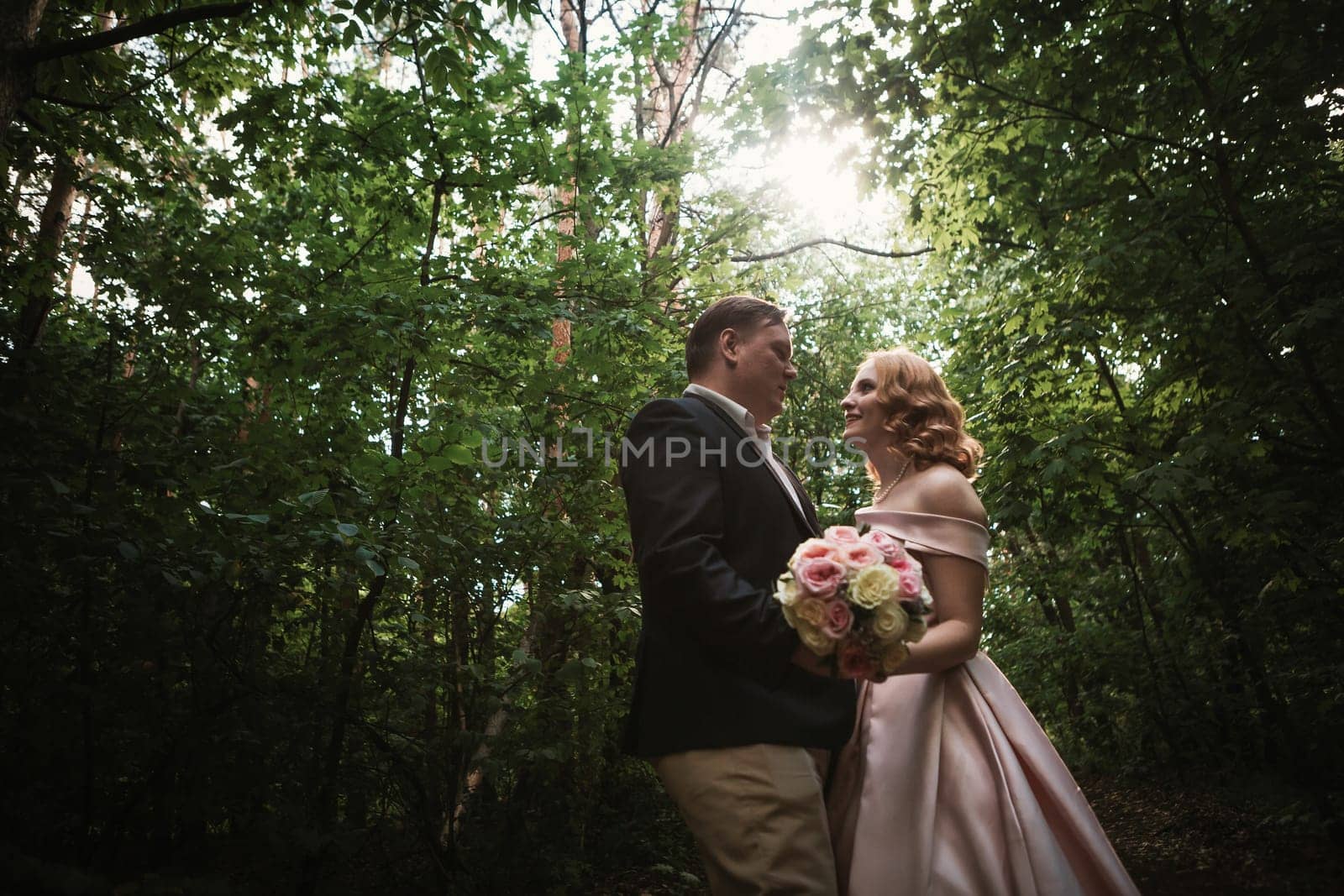 bride and groom dancing in the forest background and sunlight.