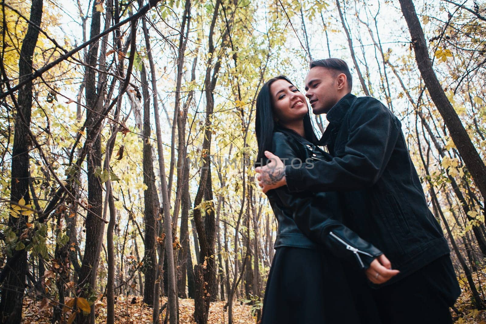 The girl and the guy are walking in the autumn forest.