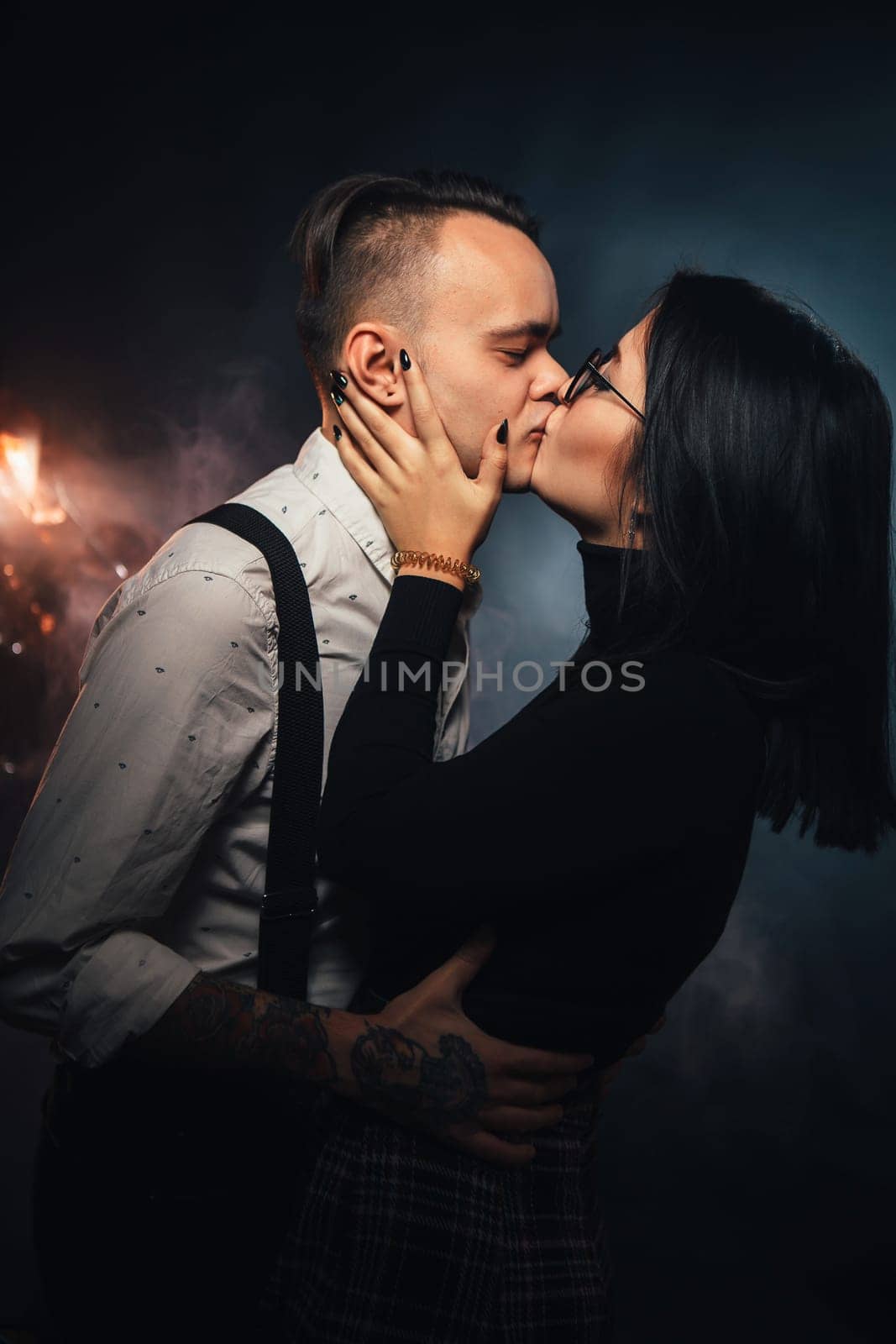 Couple in fashionable clothes on a dark background with smoke.
