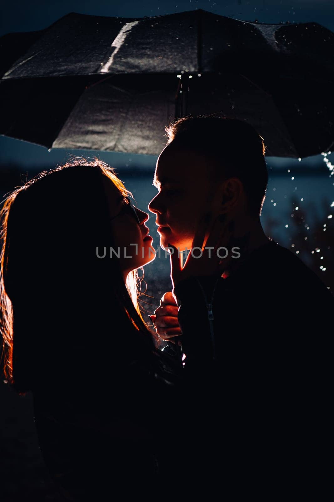 young man and woman under an umbrella and rain.