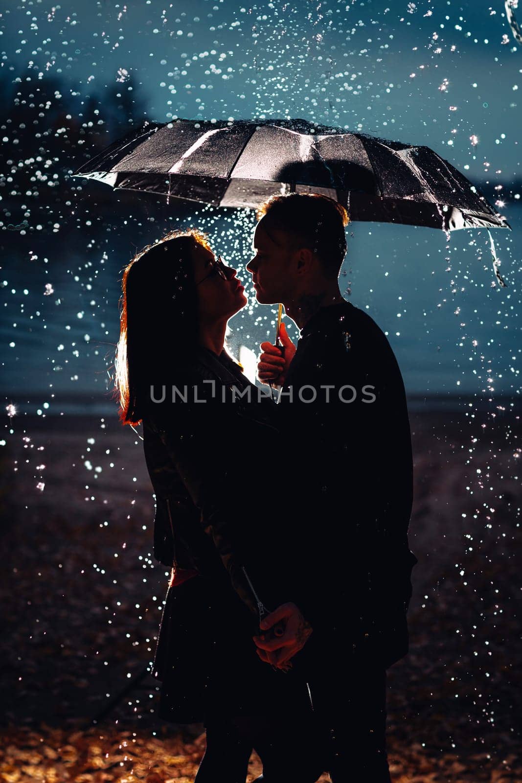 young man and woman under an umbrella and rain.