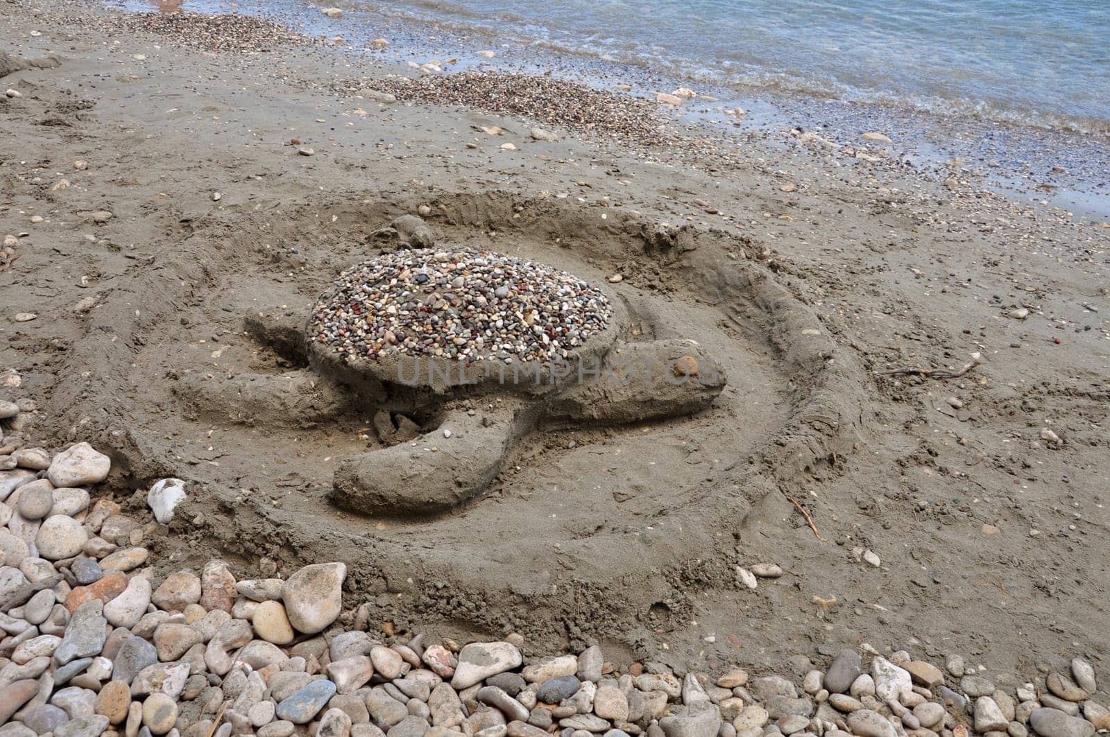 Sea turtle sand sculpture on sandy beach. Summer holidays.