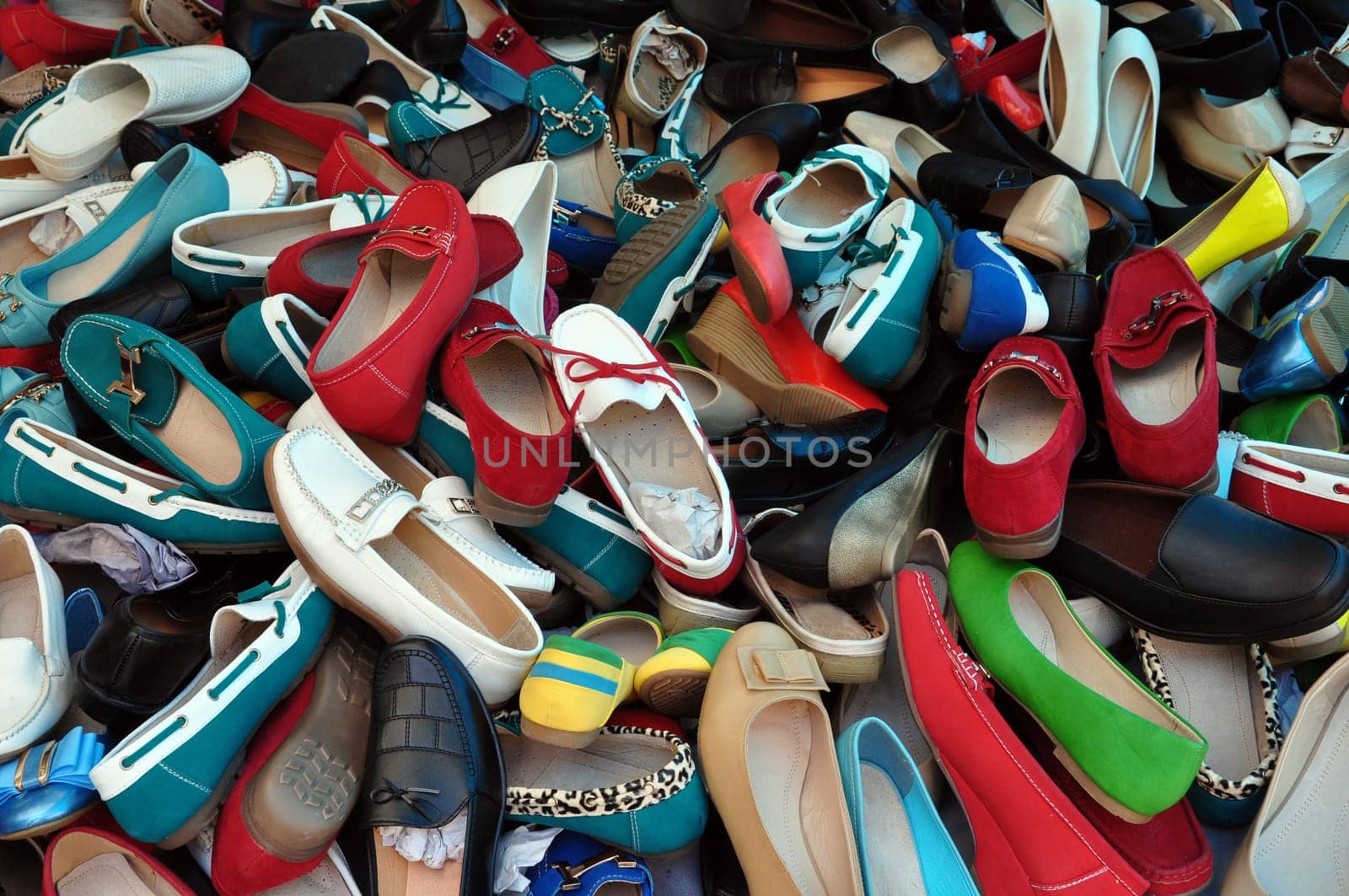 Shoes for sale at street market. Pile of assorted footwear abstract background.