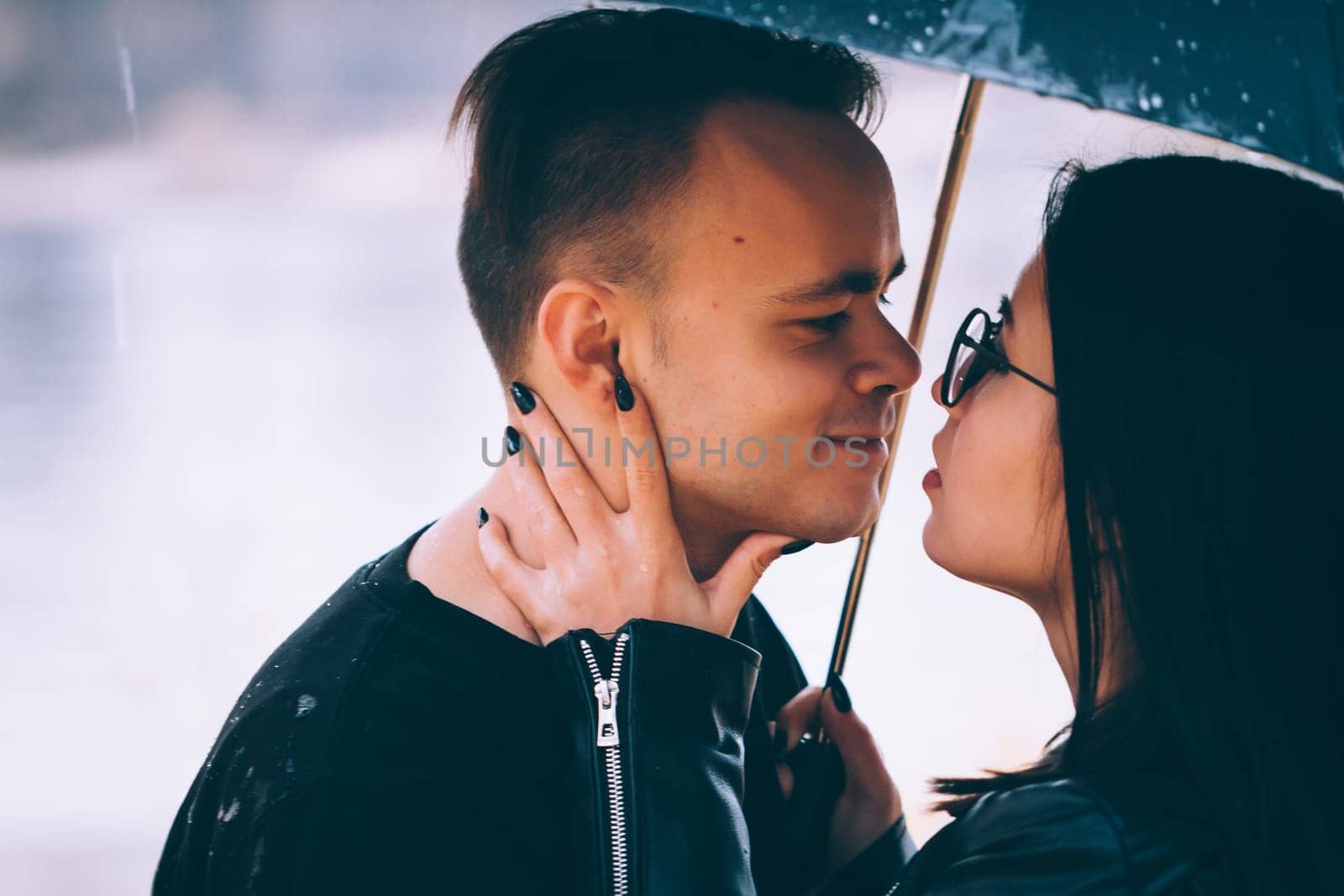young couple standing under a dark umbrella.