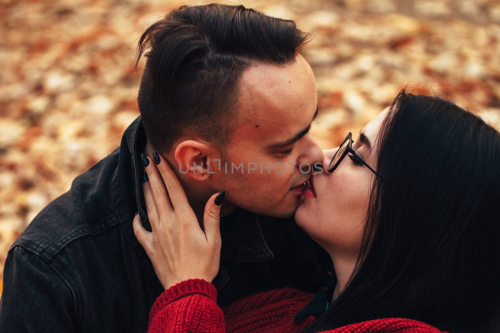 young man and young woman are sitting on a plaid in an autumn forest.